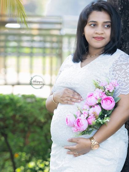 A beautiful portrait with a bouquet of pink flowers. The white lace dress and soft floral accents create a delicate and romantic feel for this maternity photo.