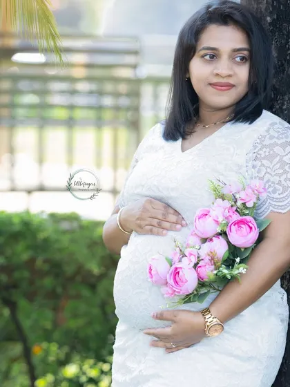 A beautiful portrait with a bouquet of pink flowers. The white lace dress and soft floral accents create a delicate and romantic feel for this maternity photo.