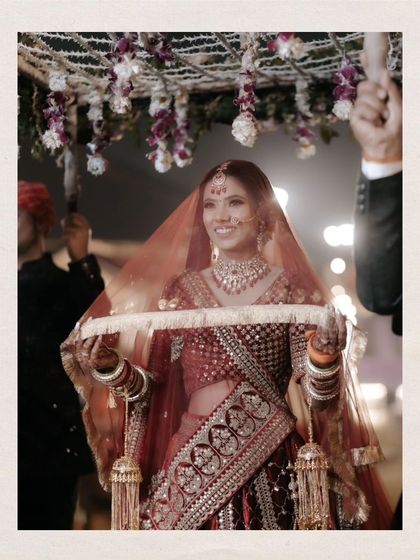 A close-up of Shalini's bridal entry, her happy smile shining as she walks under the phoolon ki chadar.