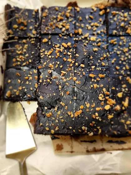 A freshly baked tray of our fudgy chocolate brownies, topped with crunchy nuts. We cut them into generous squares, perfect for grabbing one on the go or adding to a dessert platter.