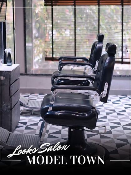 Another view of our stylish barber chairs, set against a modern, geometric-tiled floor and large windows.
