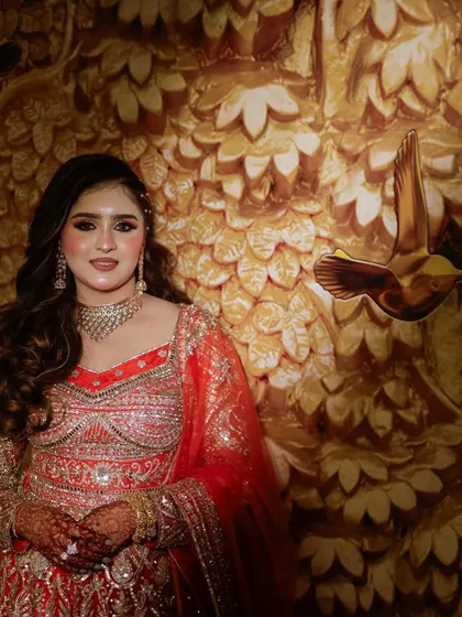 A beautiful portrait of the bride, showcasing her soft glam makeup and stunning red and gold reception outfit.