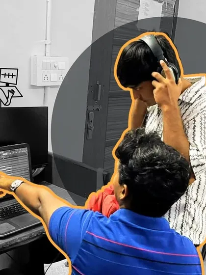One-on-one guidance is a key part of our teaching philosophy. Here, an instructor points out specific waveforms on the DAW, helping a student understand the nuances of audio editing and mixing.