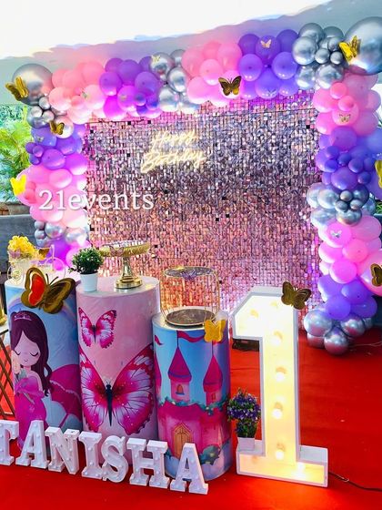 A butterfly theme with a sparkling sequin backdrop. The mix of purple and pink balloons with butterfly accents is perfect for a glamorous first birthday.