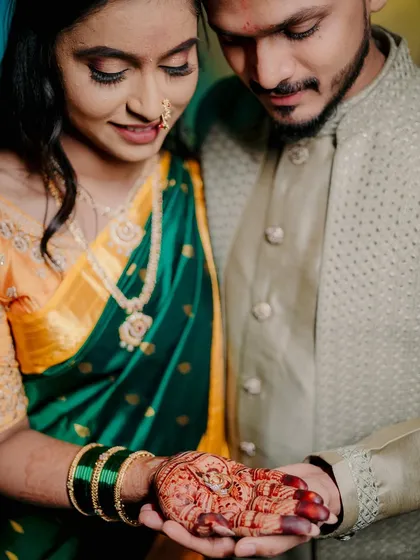 A close-up on the engagement ring, resting in the bride's henna-covered palm as the groom holds her hand. This shot beautifully combines the symbol of their commitment with traditional cultural details.
