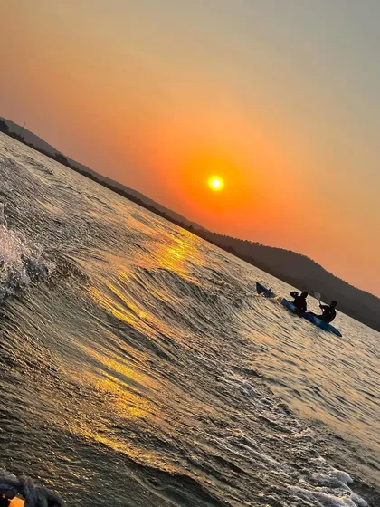 Two friends in a kayak, silhouetted against a brilliant orange sunset. This is the perfect setting for a memorable evening on the water.
