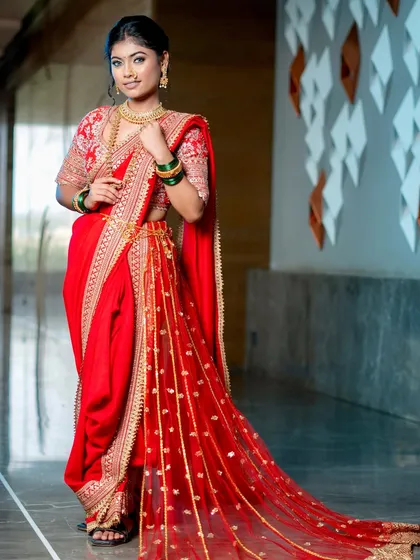 A regal portrait of a bride in a traditional red Nauvari saree. The luminous base and soft gold shimmer on the eyes let her natural beauty and the rich attire shine.