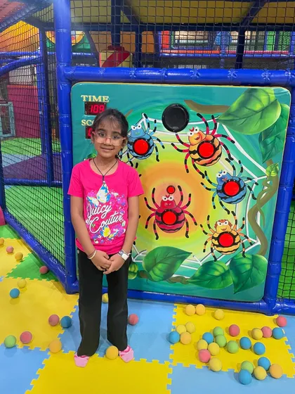 A girl stands proudly next to the interactive spider game, ready for another round of play.