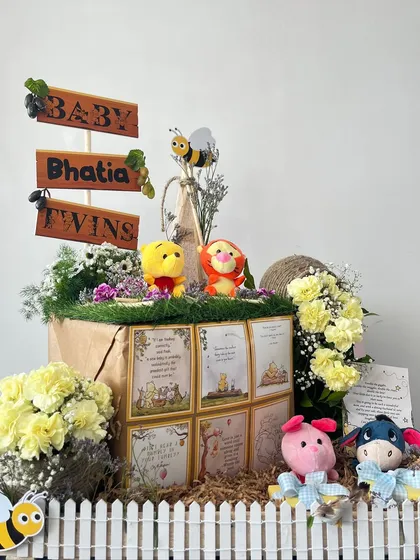 A journey into the Hundred Acre Wood to welcome the Bhatia twins. This charming Winnie the Pooh hamper is filled with character plushies, storybook quotes, and sweet treats, all nestled in a rustic, garden-like setting.