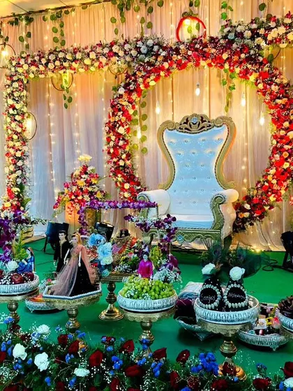 An engagement stage featuring a circular floral arch and dozens of my decorated platters. The combination of red, blue, and white flowers with elegant lighting creates a romantic and festive setting.
