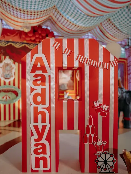 Personalization is key. This large, custom-built letter 'A' for Adhyan doubles as a decorative prop and a playful photo opportunity, featuring carnival-themed cutouts and classic red and white stripes.