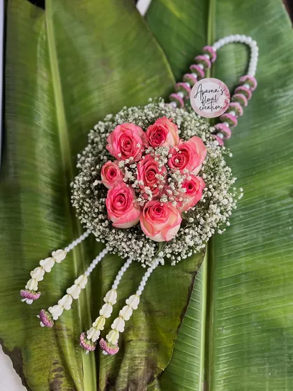 A beautiful floral purse designed as a baby shower prop. This piece features a halo of baby's breath surrounding a cluster of pink roses, with a delicate floral strap.