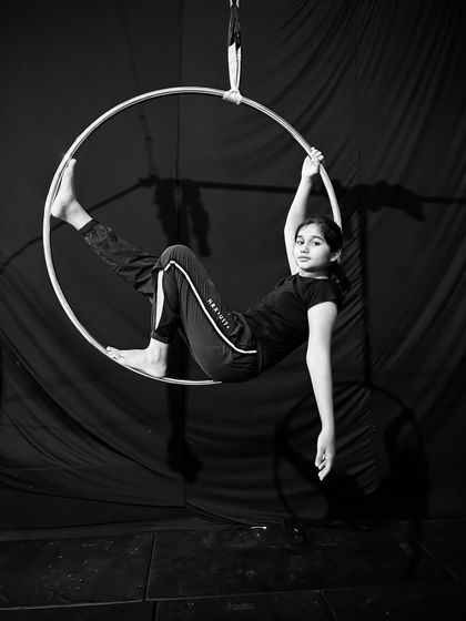A young student takes a moment to relax and pose inside the hoop, showing the fun and accessible nature of our classes.