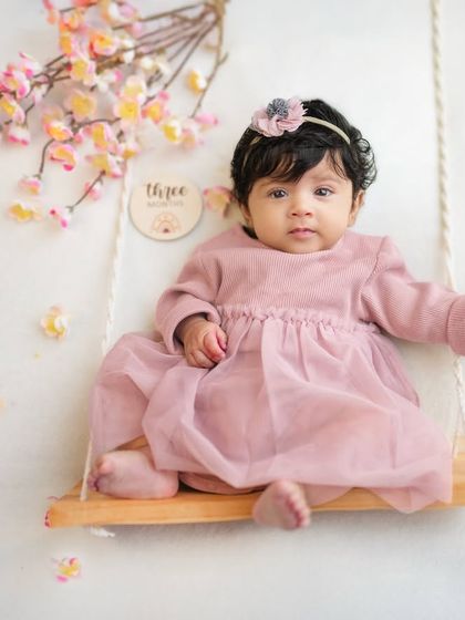 Welcoming spring with a three-month milestone session. This little one is sitting on a swing surrounded by cherry blossoms, a beautiful theme for a growing baby.