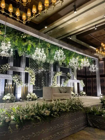 A closer view of the white and green reception stage, highlighting the intricate details of the floral arrangements and the elegant seating.