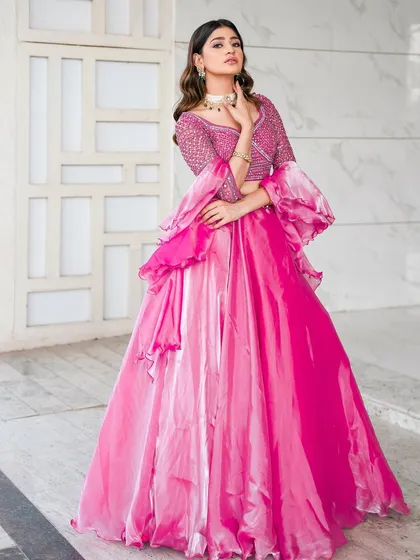 A full-length view of the rose pink lehenga with its unique tiered skirt and dramatic sleeves. This outfit is designed to make a statement and is perfect for dancing the night away.
