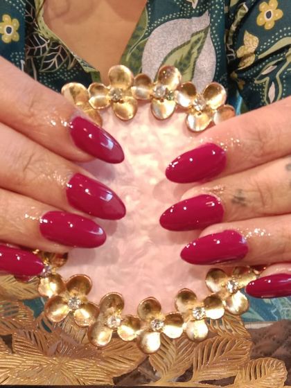 A classic and confident set of solid magenta nails in a glossy finish on almond-shaped extensions.