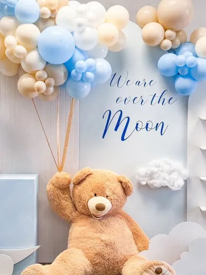 A close-up of the giant teddy bear holding a bunch of balloons in our "Over the Moon" themed baby shower setup.