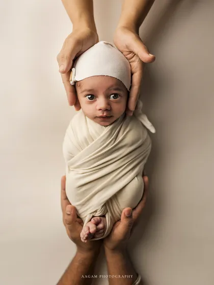 Held safely in parental hands, this little one looks right at the camera. The simple wrap and cap keep the focus on those beautiful, curious eyes.