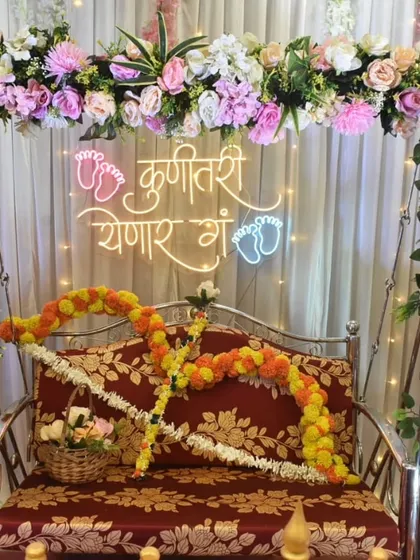 A classic and elegant Dohale Jevan setup. The floral arch around the jhula and the 'Kunitari Yenar Ga' neon sign create a perfect, timeless look for the ceremony.