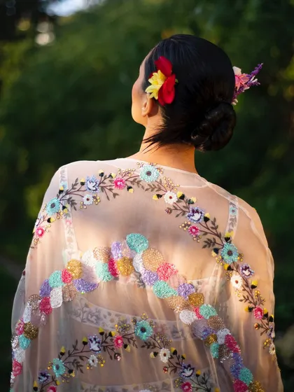 A detail shot of the exquisite, hand-embroidered cape against the light. This image highlights the sheer fabric and the incredible craftsmanship of the piece.