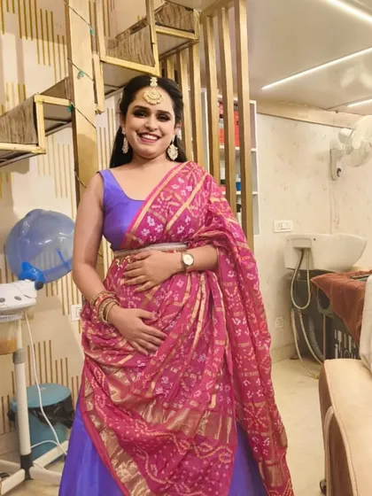 A happy client glowing after her party makeup session at our studio. She is dressed in a beautiful purple and pink traditional outfit, with her makeup and hair perfectly styled for the occasion.