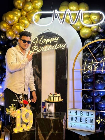 Pointing to the "Happy Birthday" sign, this guest is all smiles. Our custom neon signs and decor elements like the light-up "19" make every birthday feel personal and special.