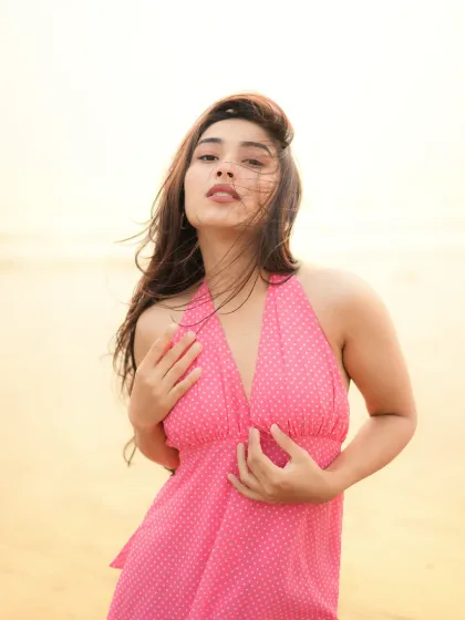 A direct and confident pose from the same beach series, with the wind catching the model's hair.
