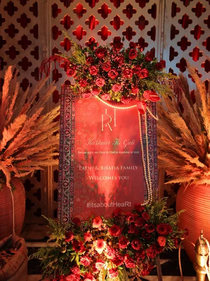The welcome signage for the "Kashmir Ki Gali" event, designed to look like a rich carpet and adorned with red roses and pearls, immediately immersing guests in the theme.