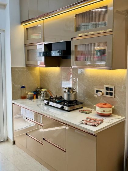 A close-up of the hob and chimney area. The fluted glass cabinets add a touch of elegance, while the high-gloss laminate is easy to clean and maintain.