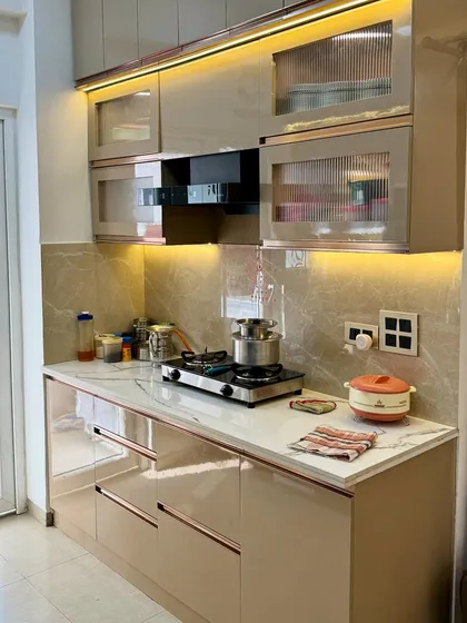 A close-up of the hob and chimney area. The fluted glass cabinets add a touch of elegance, while the high-gloss laminate is easy to clean and maintain.