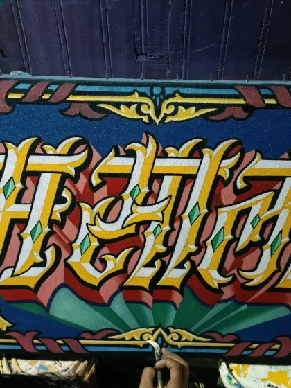 Painting a name in a highly stylized, decorative font. The complexity of the letters shows the level of detail I put into my work.