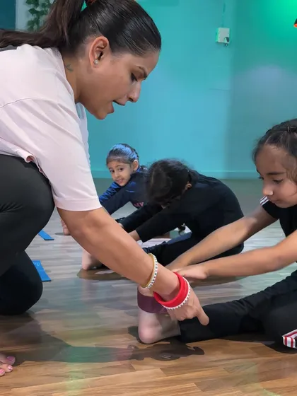 In this group setting, I'm still able to give individual corrections. I'm adjusting this student's foot alignment in a forward bend, a small tweak that ensures the stretch is targeting the right muscles.