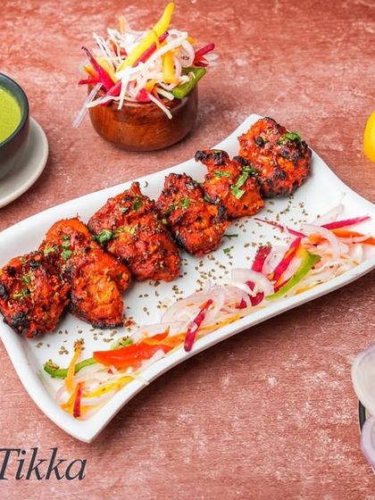 The timeless Chicken Tikka, featuring boneless chicken pieces marinated in a spicy yogurt mixture and grilled to perfection in our tandoor. It's smoky, spicy, and incredibly juicy.