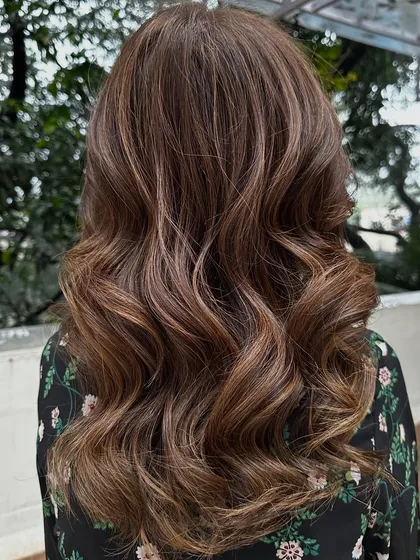 This client flew in from Dubai for my signature 'Caramello' color. I blended caramel highlights into her hair and covered her greys for a fresh, youthful look. The final style with soft waves really shows off the dimension.