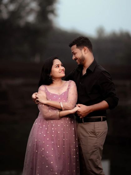 A beautiful maternity portrait taken in the soft, low light of dusk. The couple's gentle embrace and the moody atmosphere of the natural surroundings create a deeply romantic and intimate photograph.