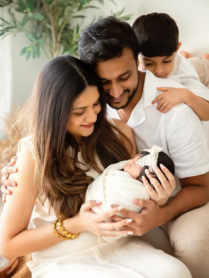 A family of four, complete with their new arrival. This portrait beautifully captures the parents' love and the older brother's gentle curiosity for his newborn sibling.