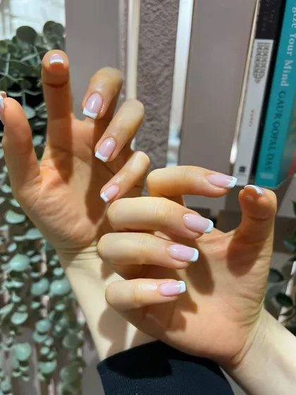 A playful pose showing off a flawless classic French manicure. It's the perfect accessory for any outfit.