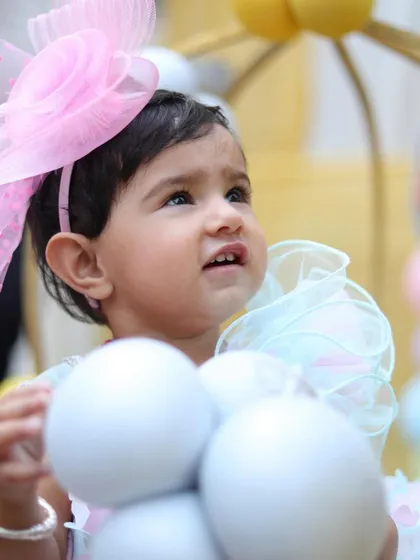 A sweet portrait of the birthday girl looking up, with a large pink bow in her hair. Close-up shots like this highlight the adorable details and expressions of your little one.