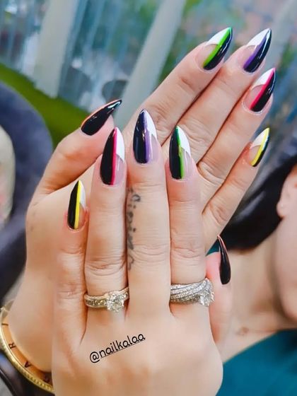 A striking design on long stiletto nails, featuring a split design with black on one side and a sliver of bright color on the other.