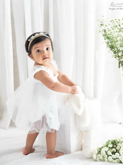 This little girl in her beautiful white tulle dress is ready for her first birthday portrait. The bright, airy setup makes her look like a little angel.