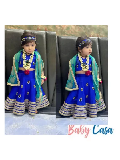 Celebrating Radha-Krishna in every little face. This royal blue lehenga choli with a sheer green dupatta is a divine outfit for a little girl celebrating Janmashtami.