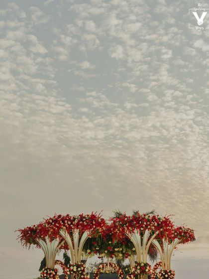A stunning shot of the magnificent floral mandap against a beautifully textured sky. This image highlights the scale and artistry of the wedding decor.