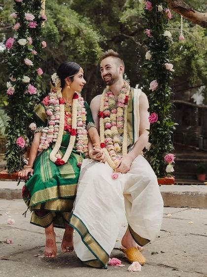 A cross-cultural couple shares a moment on the swing, surrounded by lush greenery and traditional decor.
