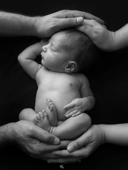 Another perspective of the "held in hands" pose, this time showing the baby's profile. The dramatic lighting in this black and white photo creates a beautiful, sculptural effect.