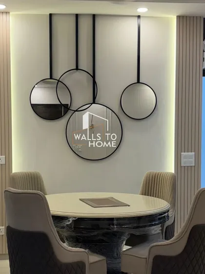 A close-up of the modern dining area accent wall. The composition of round mirrors, black metal frames, and vertical wall panels creates a sophisticated and artistic focal point.