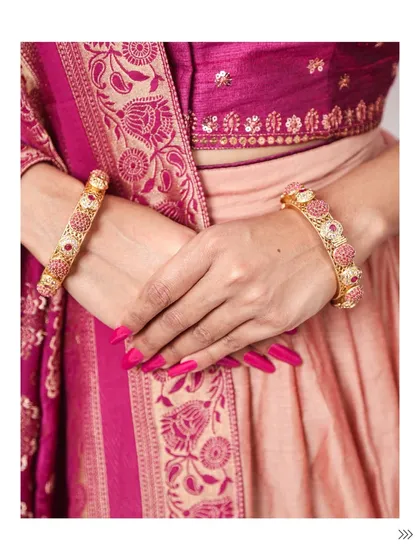 A detail shot of beautiful pink and gold bangles paired with a traditional silk outfit. The right bangles can completely elevate an ethnic look.