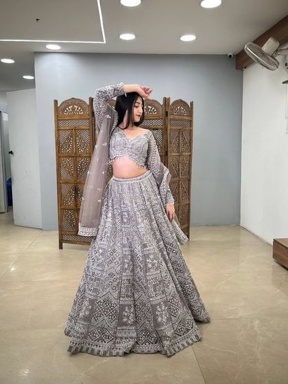 The model strikes a pose, highlighting the beautiful flare of the grey lehenga skirt. This is a perfect outfit for making a grand entrance.