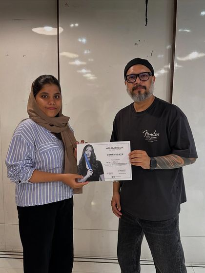 A proud student receives her certificate after completing an advanced haircut workshop with a guest artist. We celebrate every milestone on our students' paths to success.