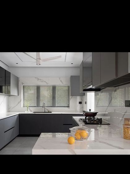 The kitchen in the 'Open Sky Residence' is sleek and modern, with handleless grey cabinets and a white marble-effect countertop and backsplash.